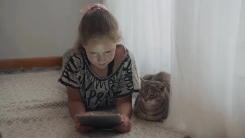 Girl next to her cat using tablet device. Young protagonist on the screen. Teen Stock Footage 130831514