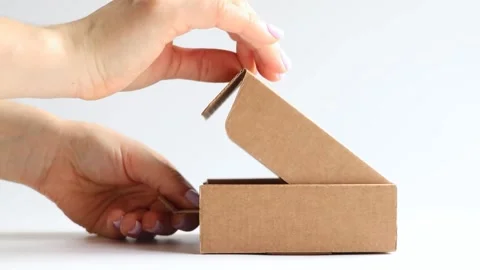 A girl opens a brown cardboard box on a white background Stock Footage 266933763