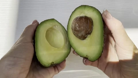 The girl opens a cut avocado Stock Footage 246975741