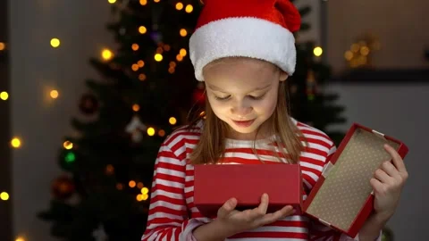 Girl opens gift box and smiles next to christmas tree. New Years present Stock Footage 320675109
