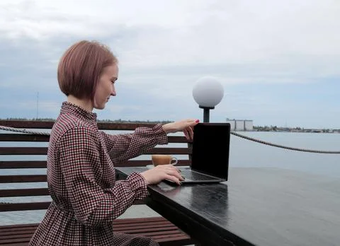Girl opens a laptop for work. at the table on the street against the backgrou Photos