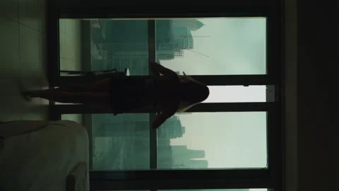 The girl opens the panoramic window. Apartment on a very high floor in Dubai 스톡 동영상 167737012