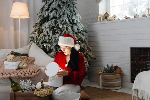 The girl opens the present. the light from the present shines on the person. A Photos