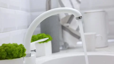 A girl opens the water in the tap in the kitchen in a modern interior. Purified Stock Footage 276805090
