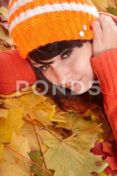 Girl in orange hat on leaves with sad face. Stock Photos