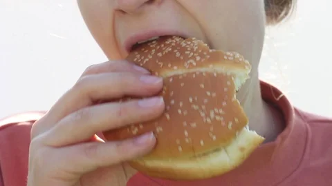 Girl in orange sweatshirt eats burger closeup Stock Footage 128098571