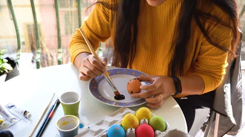 A girl paints an Easter egg in black in view of the approaching Easter Video stock 127852855