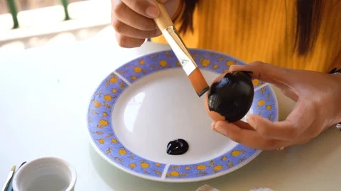 A girl paints an Easter egg with a brush in black, in view of the approaching Video stock 127853366