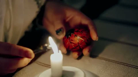 Girl paints on Easter egg. Burning candle. Video stock 61845831