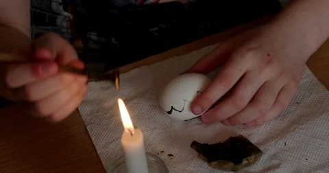 Girl Paints on Easter Egg With Candle 動画素材 62314979