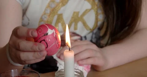 Girl Paints on Easter Egg With Candle Stockbeeldmateriaal 62315029