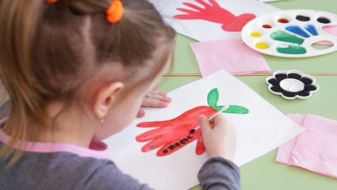 A girl paints a red flower with paint. She paints with a cotton swab. Close-up Stock Footage