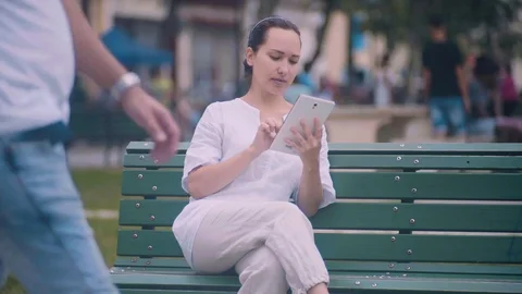 Girl in park writes a message via tablet. Stock Footage 72486730