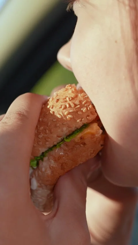 Girl passenger eats burger in car. Delicious food bun with cutlet. Teenager Stock Footage 313449132