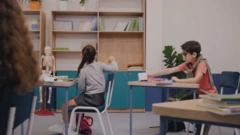 Girl passing a note to a boy behind at the classroom. Notes at elementary school Vídeo Stock 162733603