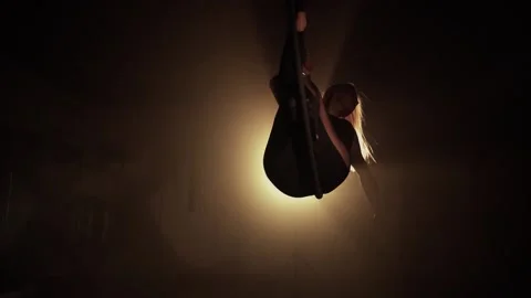 Girl performs the acrobatic elements in the air ring. Black background Slow  Stock Footage 233453541