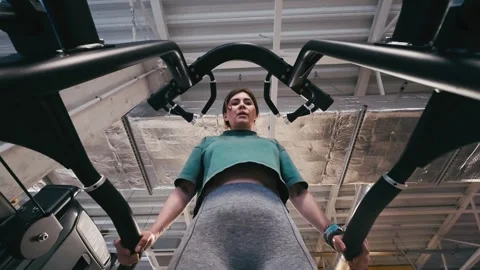 Girl Performs Assisted Dips On Parallel Bars In Gym, Legs Supported Stock Footage 322803758