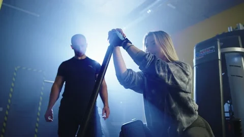 The girl performs exercises on the simulator together with professional trainer Stock Footage 235339618