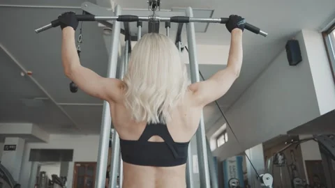 Girl performs slow motion pull-up exercise in gym showcasing strength training Video stock 302115977