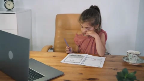 A girl performs a task in an online lesson. The child communicates online while Stock Footage 156620565