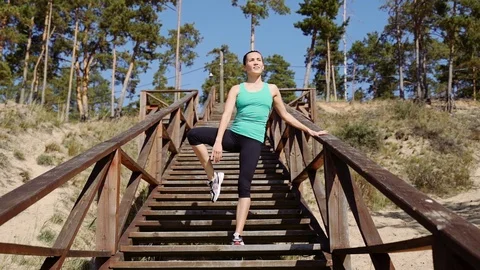 A girl performs vertical twine while standing on a wooden staircase on a steep Stock Footage 121241373