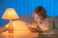 The girl with a phone lay on the bed. Evening night time Photo