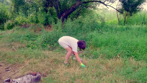 Girl picking up discarded plastic bottle Stock Footage 340463728