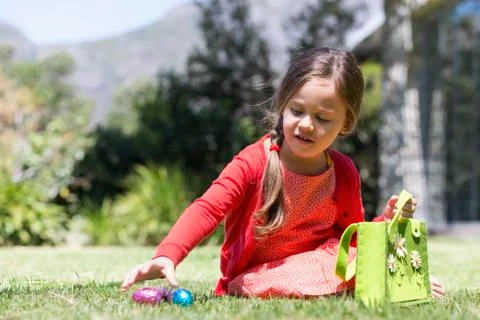 Girl picking up Easter eggs in a lawn Stock Photos