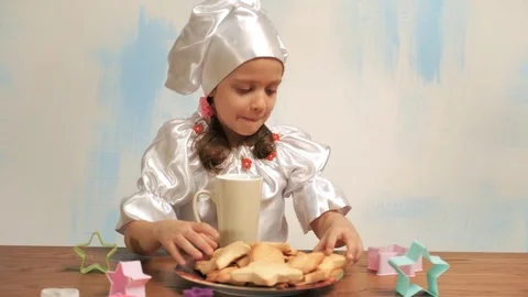 Girl picks a cookie, dunks it in milk and eat. Showing thumb up Stock Footage 73874541