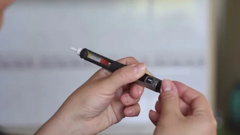 Girl picks up right dose of insulin on syringe pen Stock Footage
