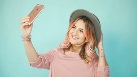 Girl in pink dress and hat make selfie on a turquoise background Stock Footage