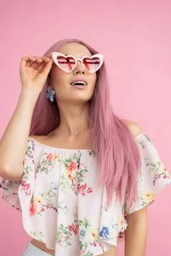Girl in pink heart-shaped glasses with pink hair looking up  Stock Photos