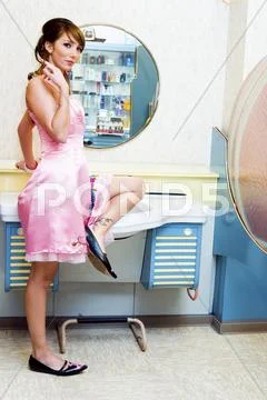 Girl in a pink petticoat in front of a blue haircutters desk Stock Photos