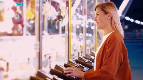 Girl plaing claw machine on a fun fair amusiment park. Night fair illumination Stock Footage 252643063