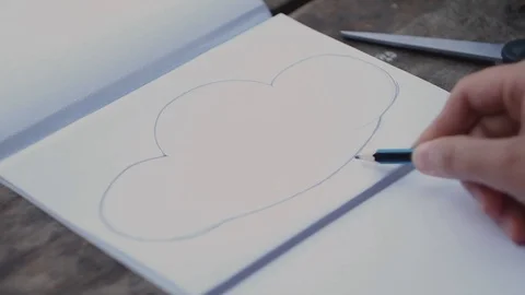 The girl plans a pencil the drawing of a cloud on paper. Stock Footage 102735945
