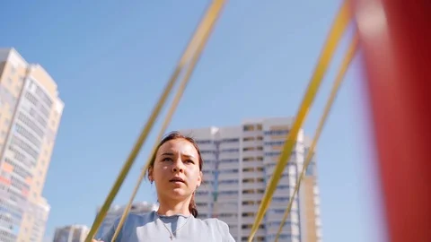 The girl on the playground does an exercise on the back muscles using a rubber Stock Footage 118819624