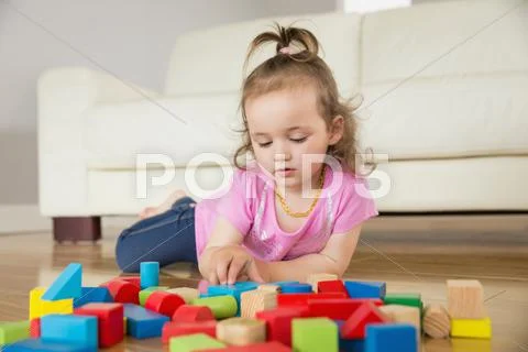 Girl playing with building blocks on floor Stock Photos