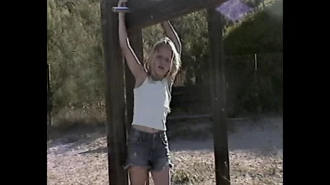 Girl playing on monkey bars in nostalgic grainy style Видео 330247495