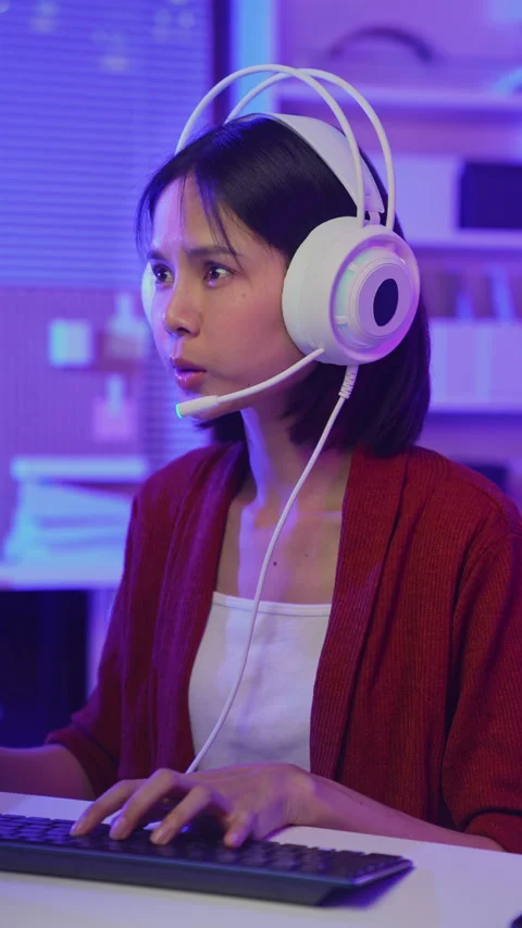 Girl playing online computer game with headset and microphone at home Stockbeeldmateriaal 335804653