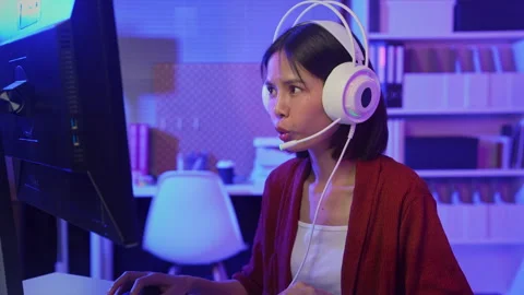 Girl playing online computer game with headset and microphone at home Stockbeeldmateriaal 335804787