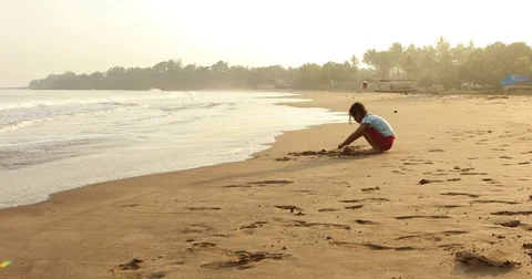 Girl playing sand alone at shore Stock Footage