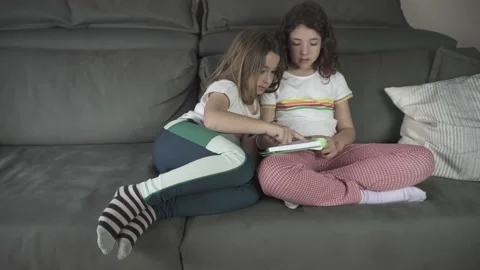 Girl playing with tablet sitting on sofa at home Stock Footage 239192583