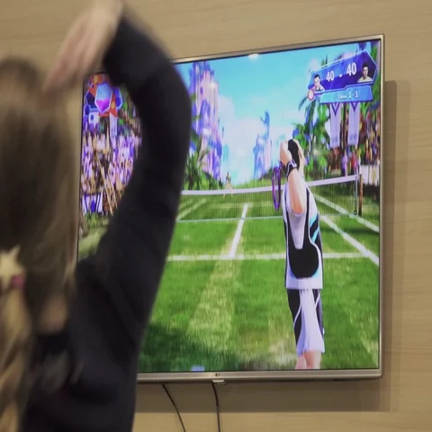 Girl playing virtual tennis game on a big screen. Stock Footage