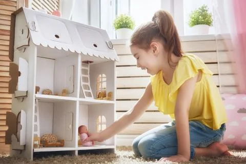 Girl plays with doll house Stock Photos