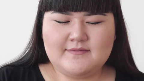 Girl plus size model eats a hamburger and smiles. cute Asian girl nibble a Stock Footage 133715572