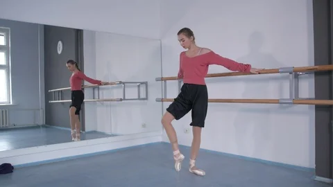 Girl in pointe doing a warm-up at the ballet choreographic machine  库存影片 106539691