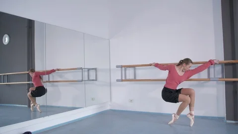 Girl in pointe doing a warm-up at the ballet choreographic machine  库存影片 106539709