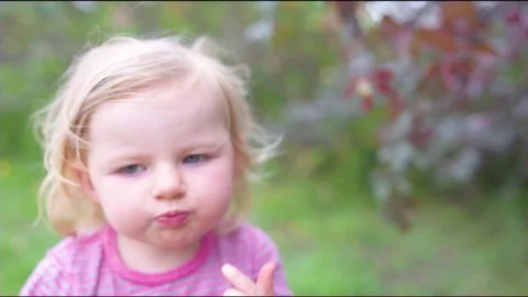 Girl pointing away while having plum in garden Stock Footage