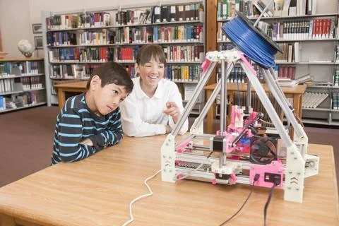 Girl points out object on 3D printer. Stock Photos