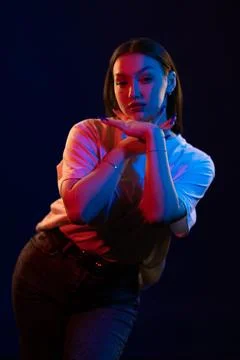 Girl posing and moving in a black studio with colored light Stock-Fotos